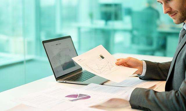 Analyst reviewing business data and legal documents at a bright Milton Keynes office desk